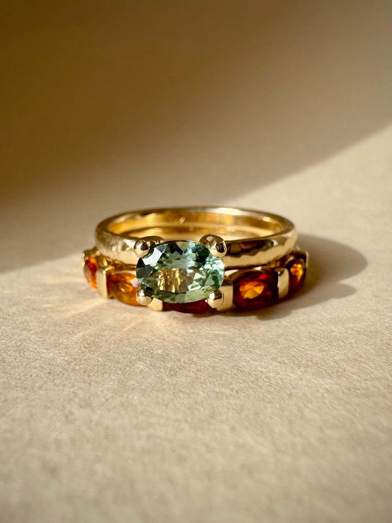 Gold ring with a green gemstone on a beige background