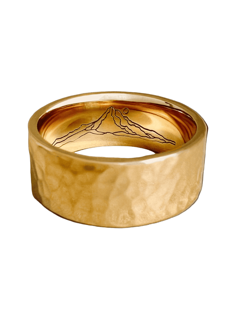 Gold ring with mountain engraving on a white background