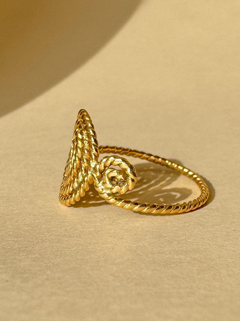 Gold spiral ring on a beige background