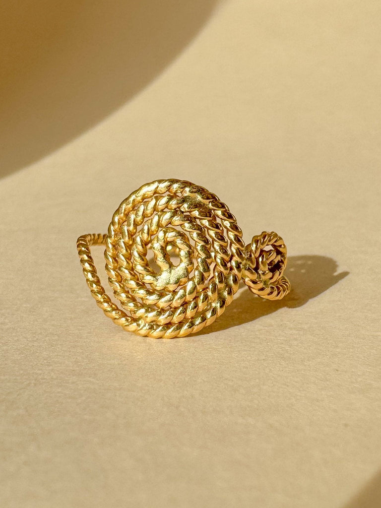 Gold spiral necklace on a beige background