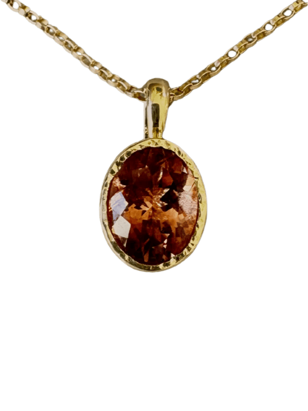 Gold necklace with a red-orange gemstone pendant on a transparent background