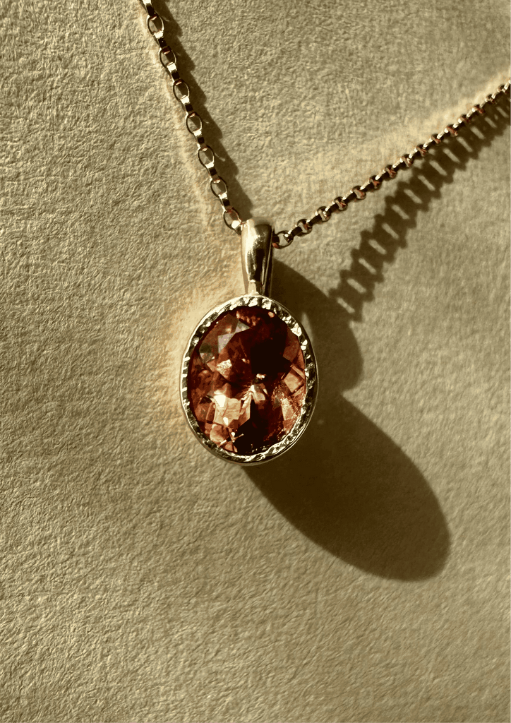 Necklace with a pendant featuring a red orange gemstone on a beige background