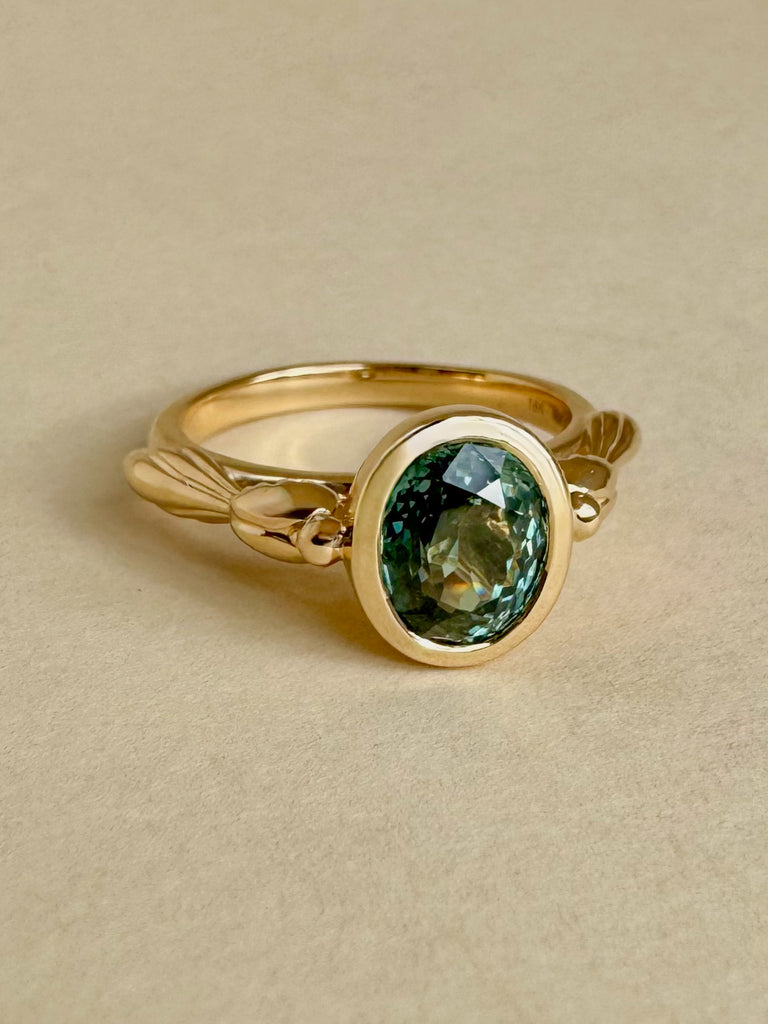 Gold ring with a green gemstone on a beige background