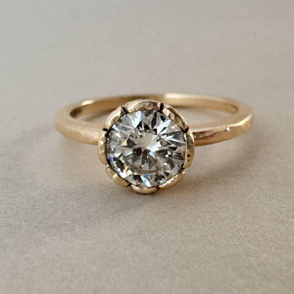 Gold ring with a large diamond on a beige background