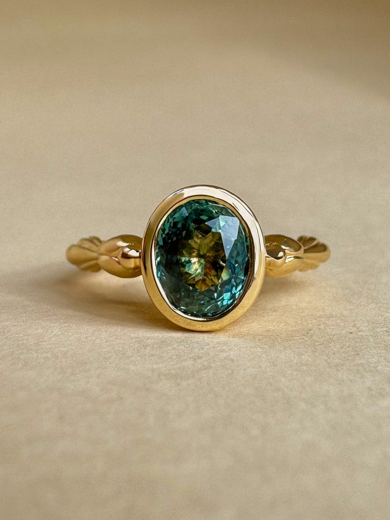 Gold ring with a green gemstone on a beige background